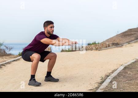 Junge Sportler Mann tut Kniebeugen im Freien Stockfoto