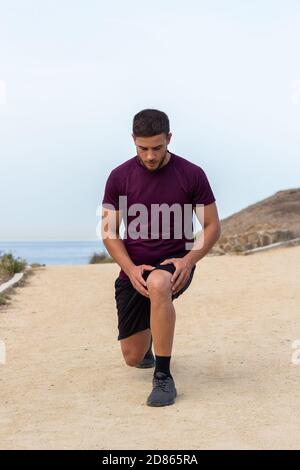 Junger Athlet Mann tut Ausfallschritte im Freien Stockfoto