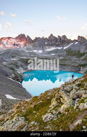 Abenteuerlicher Mann, der auf einer Klippe mit Blick auf die wunderschönen Schweizer Rockies und den Wildsee bei einem lebhaften Sonnenuntergang steht. Aufgenommen in den Schweizer Alpen, Schweiz Stockfoto