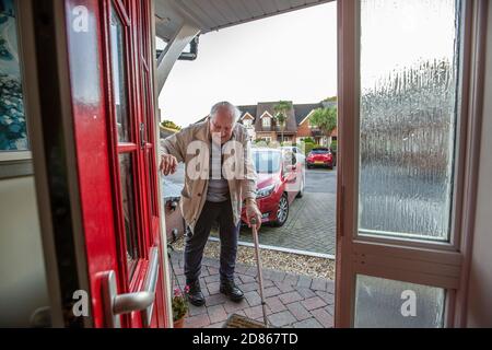 Älterer Mann in den 80er Jahren, der mit Hilfe einer Gehhilfe in sein Haus kam, Dorset, Südwestengland, Großbritannien Stockfoto