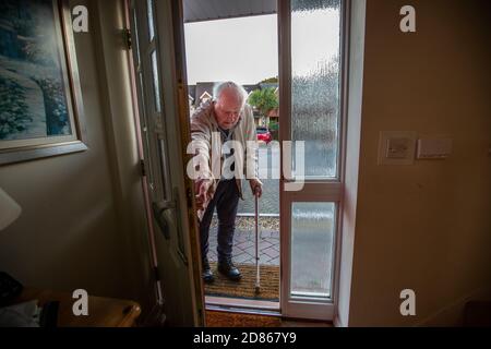 Älterer Mann in den 80er Jahren, der mit Hilfe einer Gehhilfe in sein Haus kam, Dorset, Südwestengland, Großbritannien Stockfoto
