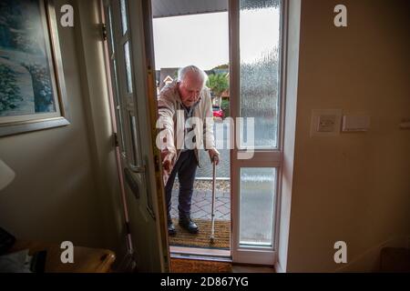 Älterer Mann in den 80er Jahren, der mit Hilfe einer Gehhilfe in sein Haus kam, Dorset, Südwestengland, Großbritannien Stockfoto