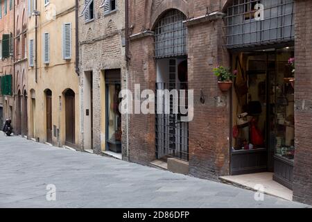 ITALIEN, TOSKANA, PROVINZ SIENA, SIENA - 07. Mai 2018: Straße von Siena, Backsteingebäude, Fenster mit grünen Fensterläden, Waschmaschine hängen an Fäden Stockfoto