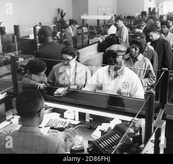 Kunden drängen die Bankgeschäfte, um ihr Bankgeschäft in der Industrial Bank, einer historischen afroamerikanischen Bank mit Sitz in Washington, DC, zu tätigen, deren Vorstand, Personal und Aktionäre Afroamerikaner, Washington, DC, 1961 sind. (Foto von Pinto/United States Information Agency/RBM Vintage Images) Stockfoto