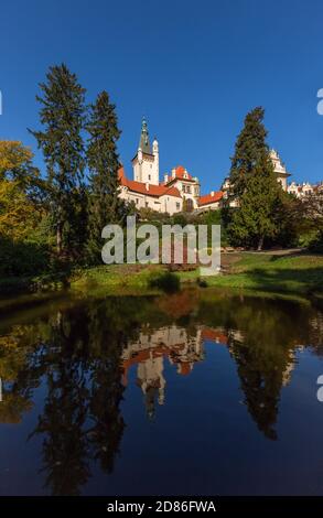 Pruhonice, Tschechische Republik - Oktober 25 2020: Blick auf die berühmte romantische Burg auf einem grünen Hügel in einem Park mit Bäumen umgeben. Reflexion Stockfoto