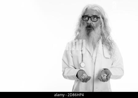 Studio shot der älteren bärtigen Mann Arzt tragen Brillen, beim Denken und halten Vitamin Tabletten Stockfoto