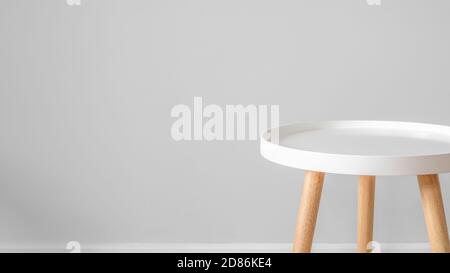 Leerer weißer Couchtisch vor grauer Wand. Skandinavischer Stil, Minimalismus im Haus, ruhiges Wohnen, Kulisse und Kopierraum für Werbung und Stockfoto
