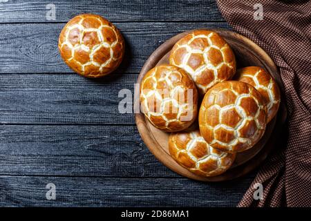 Asiatische Küche: chinesische Ananasbrötchen: Weiche und flauschige Milchbrötchen auf einem runden Schneidebrett auf dunklem Holzhintergrund, Draufsicht, Nahaufnahme Stockfoto