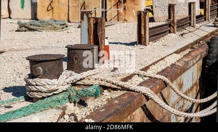 Festmacherseile auf einem rostigen Stahlbollard auf einem Deck gebunden. Schiffe sichern sich an einem alten Industriehafen Kai Stockfoto