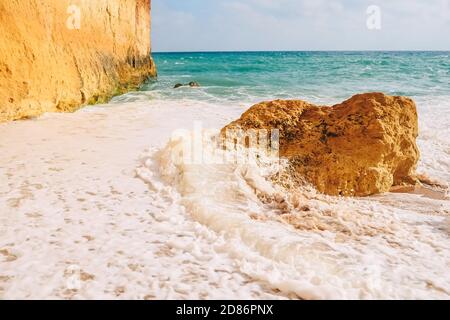 Wellen schlagen auf Felsen an den sandigen Ufern von benagil Strand in portugal Stockfoto