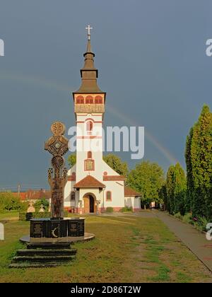 Sonnenbeschienenen Himmelfahrt Kirche gegen einen dunklen Himmel mit Regenbogen in Orastie, Rumänien Stockfoto