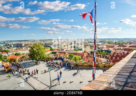 Blick auf die Stadt und die Skyline von der Spitze der Prager Burg mit Touristen unten und eine tschechische Flagge fliegen auf einem Fahnenmast. Stockfoto