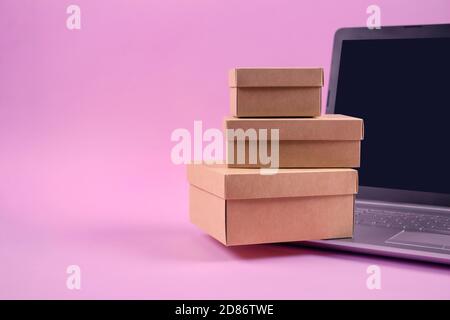 Vorderansicht auf Laptop-Computer und Verpackung Geschenk-Boxen auf pastellrosa Hintergrund mit Copyspace für Ihren Text. Saisonaler Verkauf, schwarzer freitag und Stockfoto