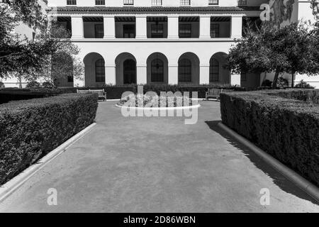 Monochromes Beispiel für Mediterranean Revival und Spanish Colonial Revival Styles mit gewölbtem Portikus und formalem Garten. Stockfoto