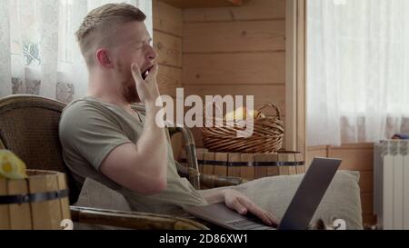 Junge müde gut aussehende Geschäftsmann Kerl in Freizeitkleidung arbeiten zu Hause, gähnt Stockfoto