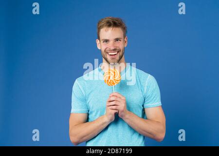 Geschmack der Kindheit. Mann mit Borsten mag Lollipop. Cheat meal Konzept. Zucker schädlich für die Gesundheit. Kerl halten Lollipop candy violett unterlegt. Mann schöner macho Essen großen bunten süßen Lutscher. Stockfoto