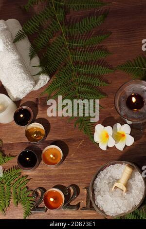 Goldene Nummern 2021 einer brennenden Kerze und ein Set für Spa-Behandlungen mit weißem Meersalz auf einem Holztisch. Stockfoto