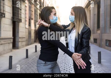 Zwei Mädchen tanzen mitten auf der Straße. Sie tragen eine Gesichtsmaske. Konzept der neuen Normalität. Stockfoto