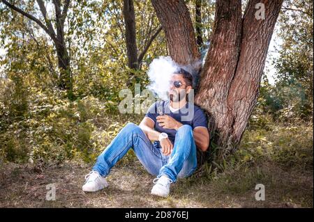 Moderne Vaper genießen eine elektronische Zigarette in der Natur. Verdampfung. Stockfoto