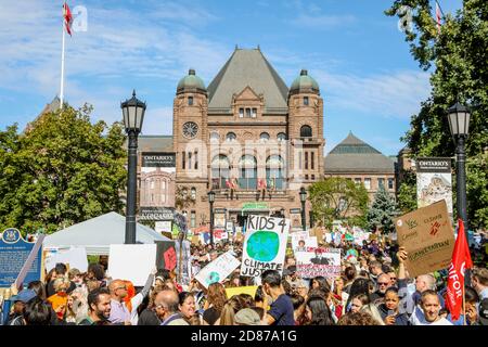 Demonstranten versammeln sich im Queen's Park, während sie Plakate halten, die ihre Meinung während der Demonstration ausdrücken.Tausende marschierten am Freitag in der Stadt Toronto zu zukünftigen Demonstrationen, um das Bewusstsein für die Probleme des Klimawandels zu schärfen. Stockfoto