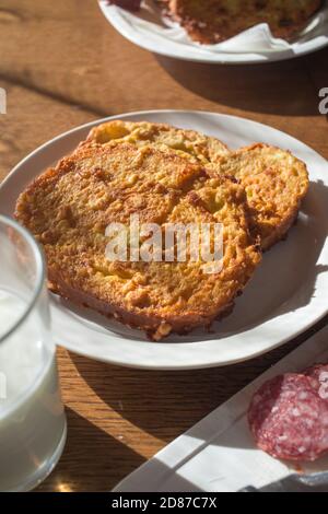 Essen und Getränke zum Frühstück und Brunch. French Toast auf einem weißen Teller, Scheiben Wurst und ein Glas Milch. Stockfoto