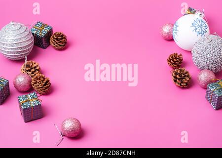 Komposition zum Weihnachtsneujahr. Geschenke, Tannenzapfen, silberne Kugel Dekorationen auf rosa Hintergrund. Winterurlaub Konzept. Flach liegend, Winkelansicht Stockfoto