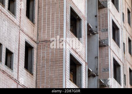 Hohe mehrstöckige verlassene sowjetische Gebäude geflieste Fassade. Verwitterte Hausarchitektur, unvollendete Stadt der Atomwissenschaftler in Birky, Ukraine Stockfoto