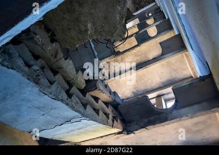 Abgestürzte Betontreppe im verlassenen zerstörten Gebäude. Blick auf das zerstörte verwitterte mehrstöckige Haus Stockfoto