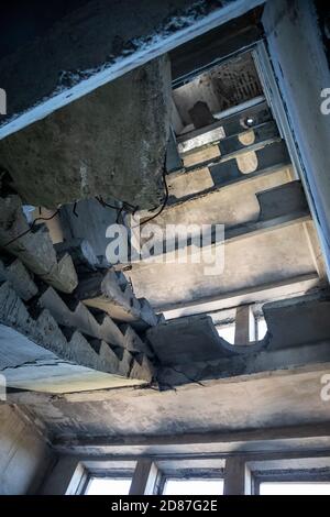 Abgestürzte Betontreppe im verlassenen zerstörten Gebäude. Blick auf das zerstörte verwitterte mehrstöckige Haus Stockfoto