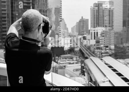 Rückansicht des kahlen Senior touristische Mann, die Bilder von der Aussicht auf die Stadt in Bangkok, Thailand Stockfoto