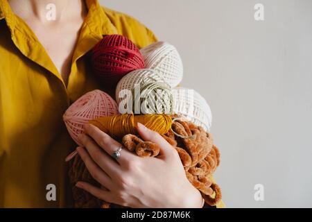 Rollen von Baumwollseilen in Frauenhand. Stricken, Häkeln, handgemachtes Hobby-Konzept Stockfoto