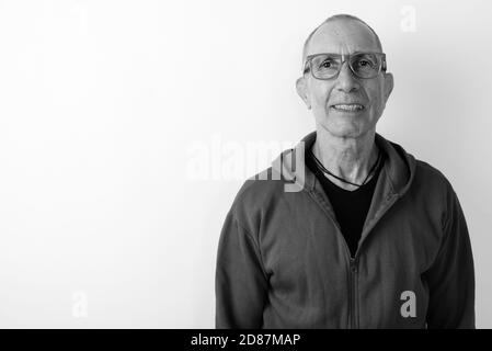 Studio shot von Happy kahlen älterer Mann lächelnd beim Tragen von Brillen vor weißem Hintergrund Stockfoto