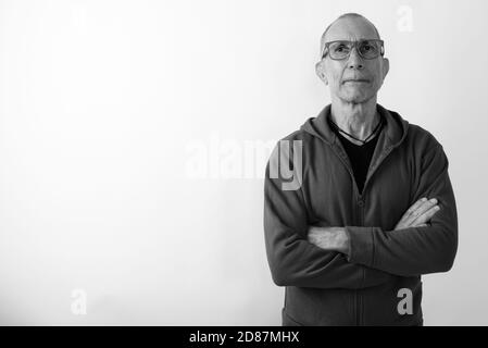 Studio shot der kahlen älterer Mann Brille tragen mit Waffen gegen weißen Hintergrund gekreuzt Stockfoto