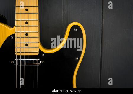 Details einer klassischen E-Gitarre in Gelb und Schwarz mit Bünden, Saiten, Hals und Mikrofon Stockfoto