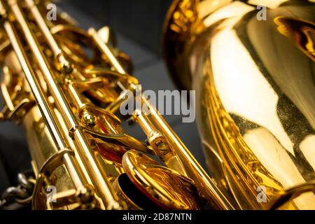 Körper, Stäbe, Schlüssel und Glocke eines goldenen Saxophons auf grauem Holzhintergrund Stockfoto