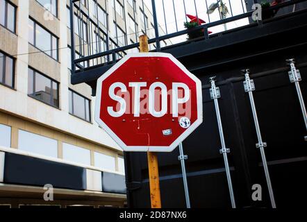 Rotes Schild mit geschriebenem englischem Wort Stop im städtischen Hintergrund Stockfoto