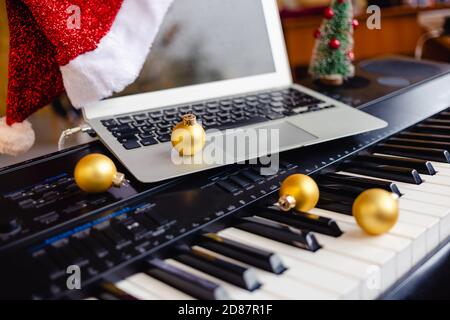 Weihnachtskugel und Laptop mit weihnachtsmütze auf Klaviertasten. Stockfoto