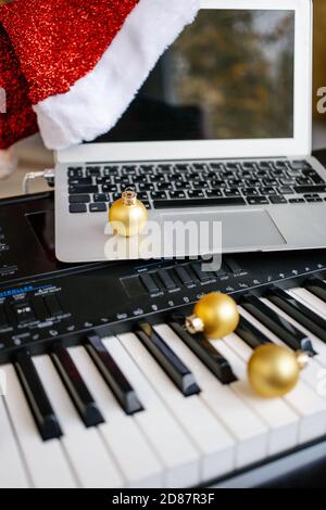 Weihnachtskugeln und Laptop mit weihnachtsmütze auf Klaviertasten. Stockfoto