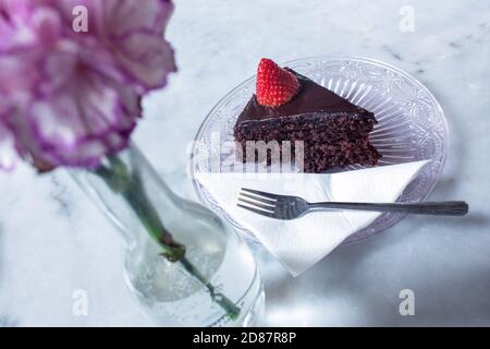 Top Schuss von einem leckeren Stück Schokoladenkuchen mit Erdbeere auf einer Glasuntertasse Stockfoto