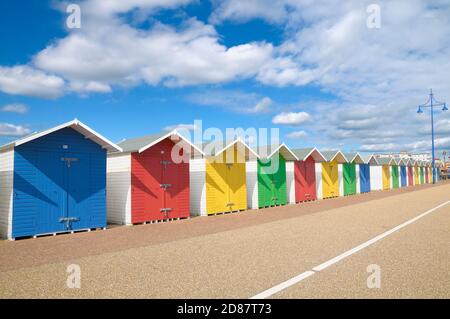 Eine Reihe von bunten hölzernen Strandhütten in strahlendem Sonnenschein mit blauem Himmel und Wolken, Eastbourne, East Sussex, England, Großbritannien Stockfoto