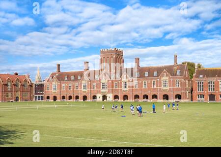 Außenansicht des Eastbourne College, einer unabhängigen öffentlichen Schule mit Studenten, die Rugby auf dem Sportplatz üben. East Sussex, England, Großbritannien Stockfoto