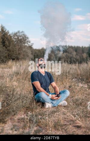 Stylish brutalen vape Mann mit elektronischen Zigarette zu vape statt zu rauchen. Mann mag wirklich Prozess des Rauchens. Stockfoto