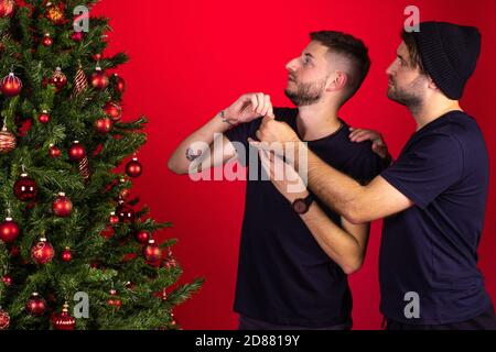 Attraktive männliche homosexuelle Paar Dekoration Weihnachtsbaum zusammen, Frohe Weihnachten Stockfoto