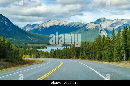 Landstraße im Wald mit Bergen im Hintergrund. Alberta Highway 11 (David Thompson Highway) entlang des Abraham Lake Ufers. Jasper-Nationalpark Stockfoto