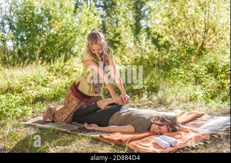 Girl Masseuse gibt ihrem Kunden eine erfrischende Massage in der ruhigen Natur. Stockfoto