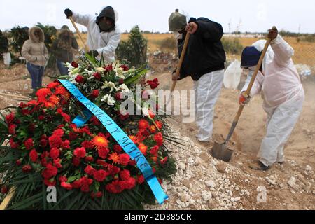 Ciudad Juarez, MEXIKO. Oktober 2020. Friedhofsarbeiter begraben die Leichen von Menschen, die mit COVID-19 infiziert wurden, in Ciudad Juarez, als eine Rauchsäule aus dem Krematorium des städtischen Friedhofs San Rafael aufsteigt. COVID-19 Opfer werden in einem separaten Teil des Friedhofs begraben. Heute erreichte Mexiko insgesamt 900,000 Fälle und fast 90,000 Todesfälle durch COVID-19. Quelle: Corrie Boudreaux/Alamy Live News Stockfoto