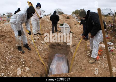 Ciudad Juarez, MEXIKO. Oktober 2020. Friedhofsarbeiter begraben die Leichen von Menschen, die mit COVID-19 infiziert wurden, in Ciudad Juarez, als eine Rauchsäule aus dem Krematorium des städtischen Friedhofs San Rafael aufsteigt. COVID-19 Opfer werden in einem separaten Teil des Friedhofs begraben. Heute erreichte Mexiko insgesamt 900,000 Fälle und fast 90,000 Todesfälle durch COVID-19. Quelle: Corrie Boudreaux/Alamy Live News Stockfoto