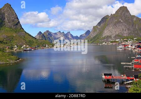 Scharfe Berge, rote Hütten und Fischerboote spiegeln sich in den Fjord in reine, Lofoten Islands, Norwegen Stockfoto