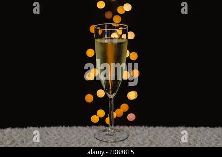 Ein Glas Sekt mit Bokeh-Lichtern auf dunklem Hintergrund. Stockfoto