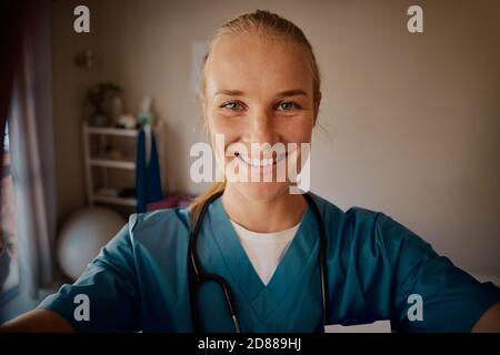 Porträt einer lächelnden Ärztin in Uniform mit Stethoskop in Nackenschauen auf die Kamera Stockfoto